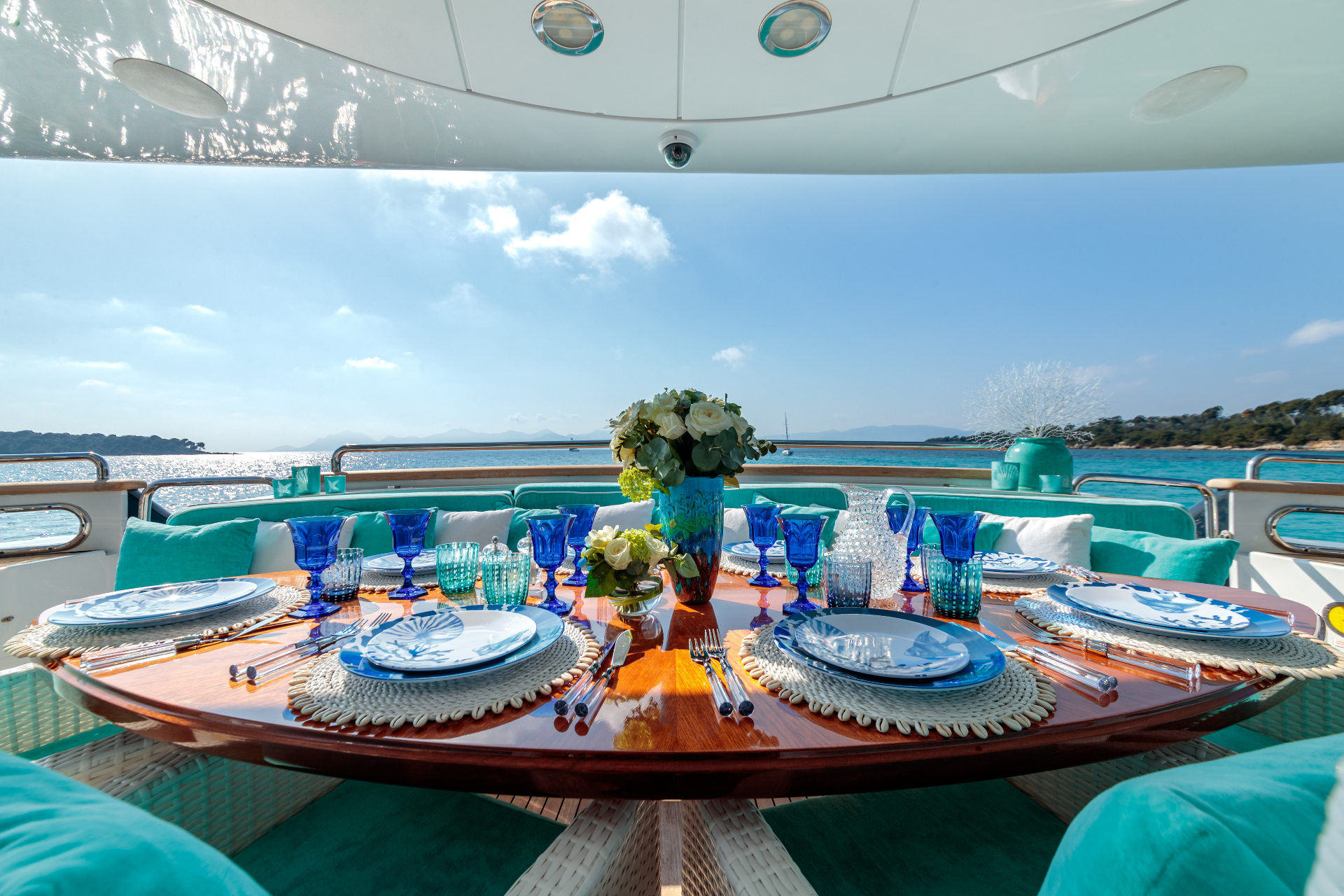 Alfresco dining table set on a yacht aft deck overlooking turquoise water