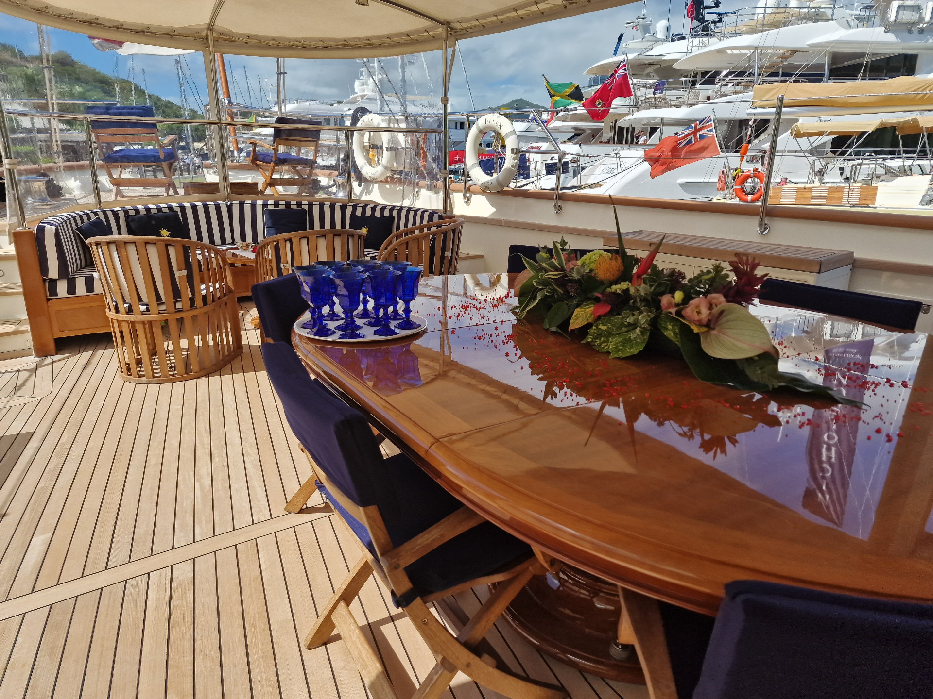 Aft-deck lounge — luxury crewed yacht in the Caribbean Aft-deck lounge and shaded dining area aboard a luxury crewed yacht moored in a Caribbean harbour at golden hour
