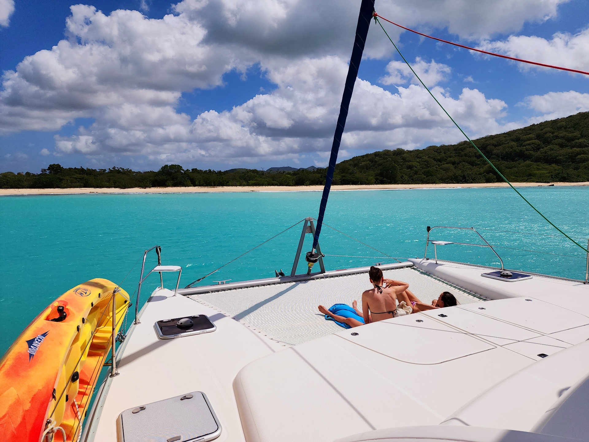 Kids jumping off the catamaran — Grenadines family sailing holiday Two children jumping off a catamaran trampoline into turquoise Caribbean water in the Grenadines